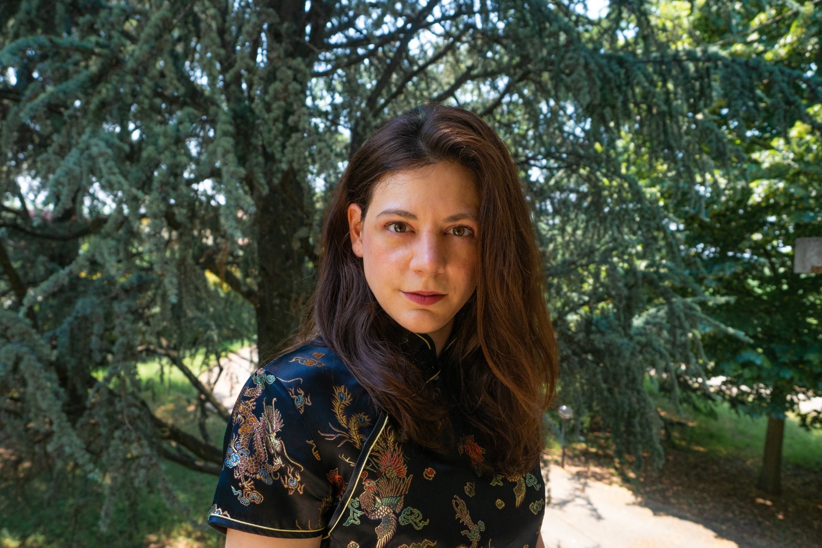 Ritratto di Lucia Vescovini, l'autrice del libro, all'aperto davanti a un grande cedro